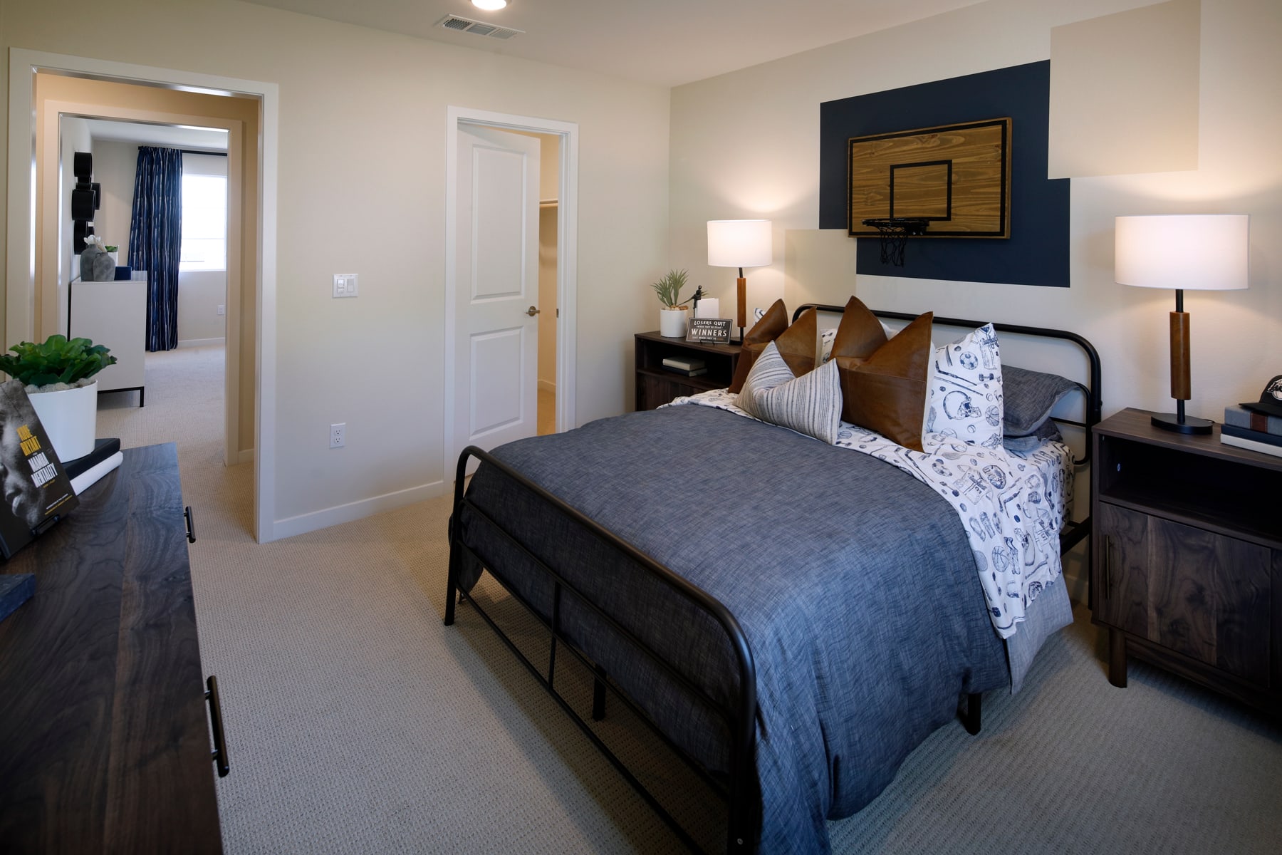 A cozy and well-decorated bedroom with a dark-colored bed frame, patterned bedding, and decorative accents on the walls, including a framed artwork above the bed.
