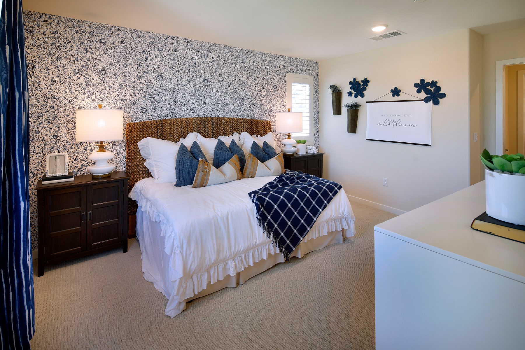 A cozy and well-decorated bedroom with a woven headboard, plush bedding, and decorative wall accents, creating a warm and inviting atmosphere.