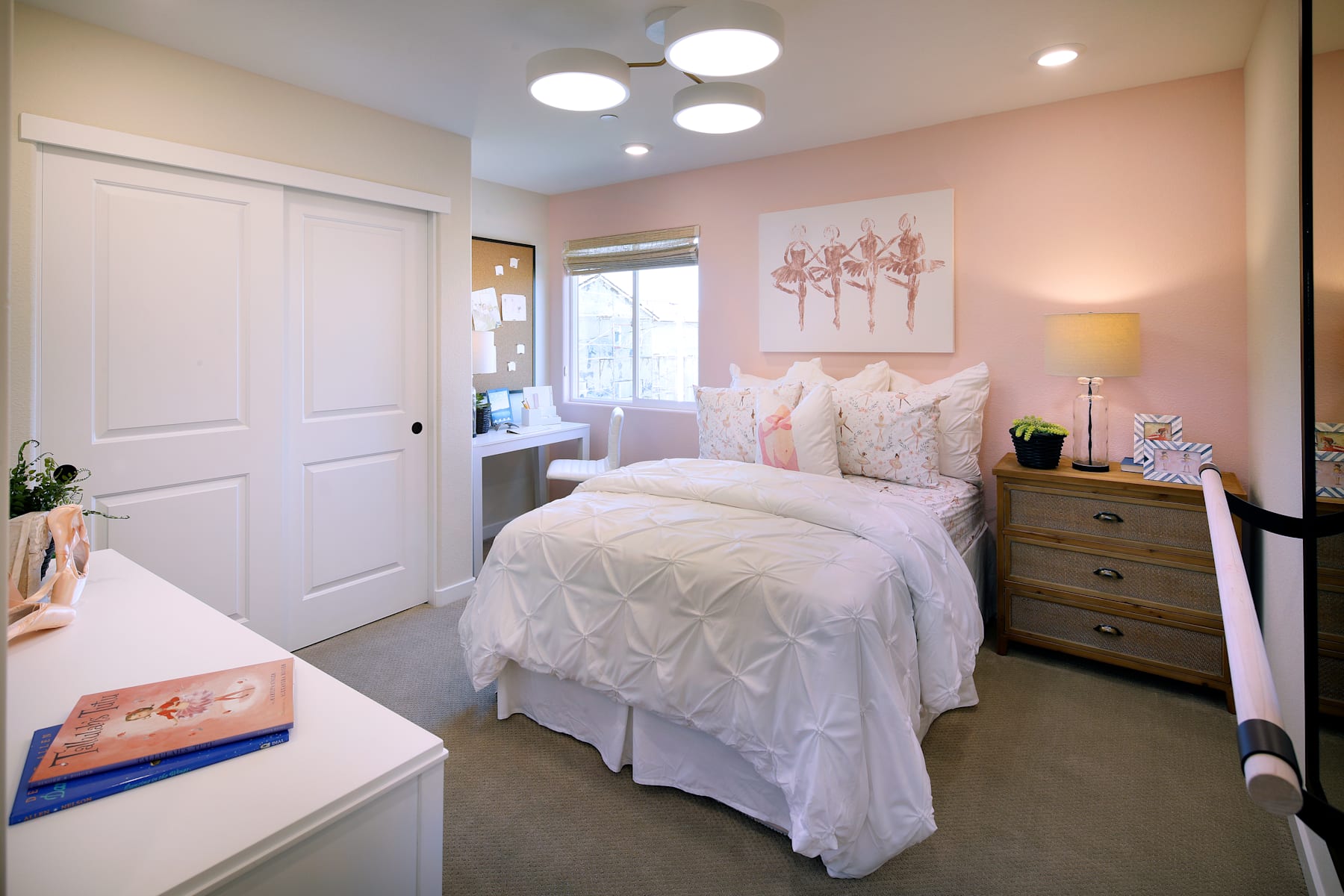 A cozy and feminine bedroom with a white bed, pink walls, and various decorative elements, including a painting and lighting fixtures.