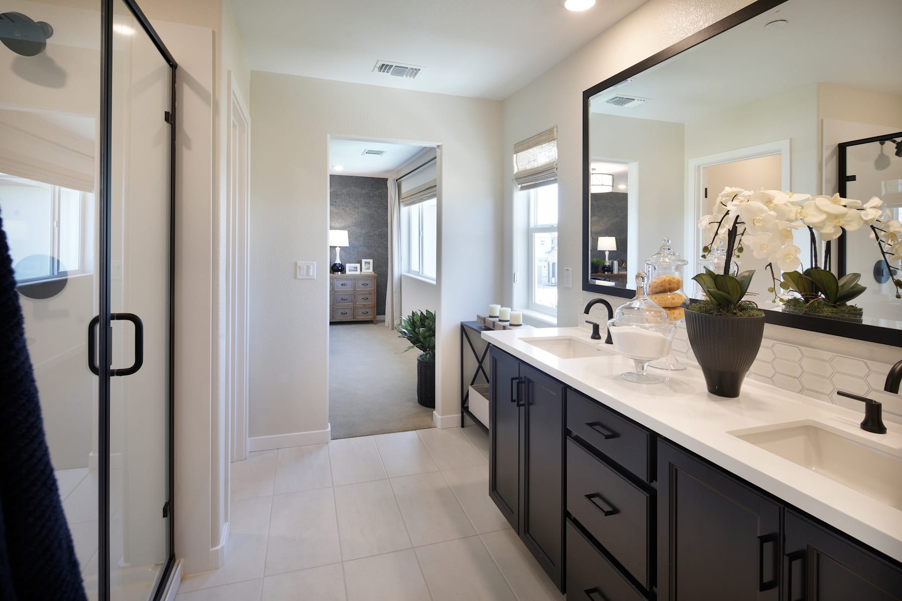 A modern and well-designed bathroom with a long vanity, dark cabinets, and a large mirror, surrounded by neutral-toned walls and floors.