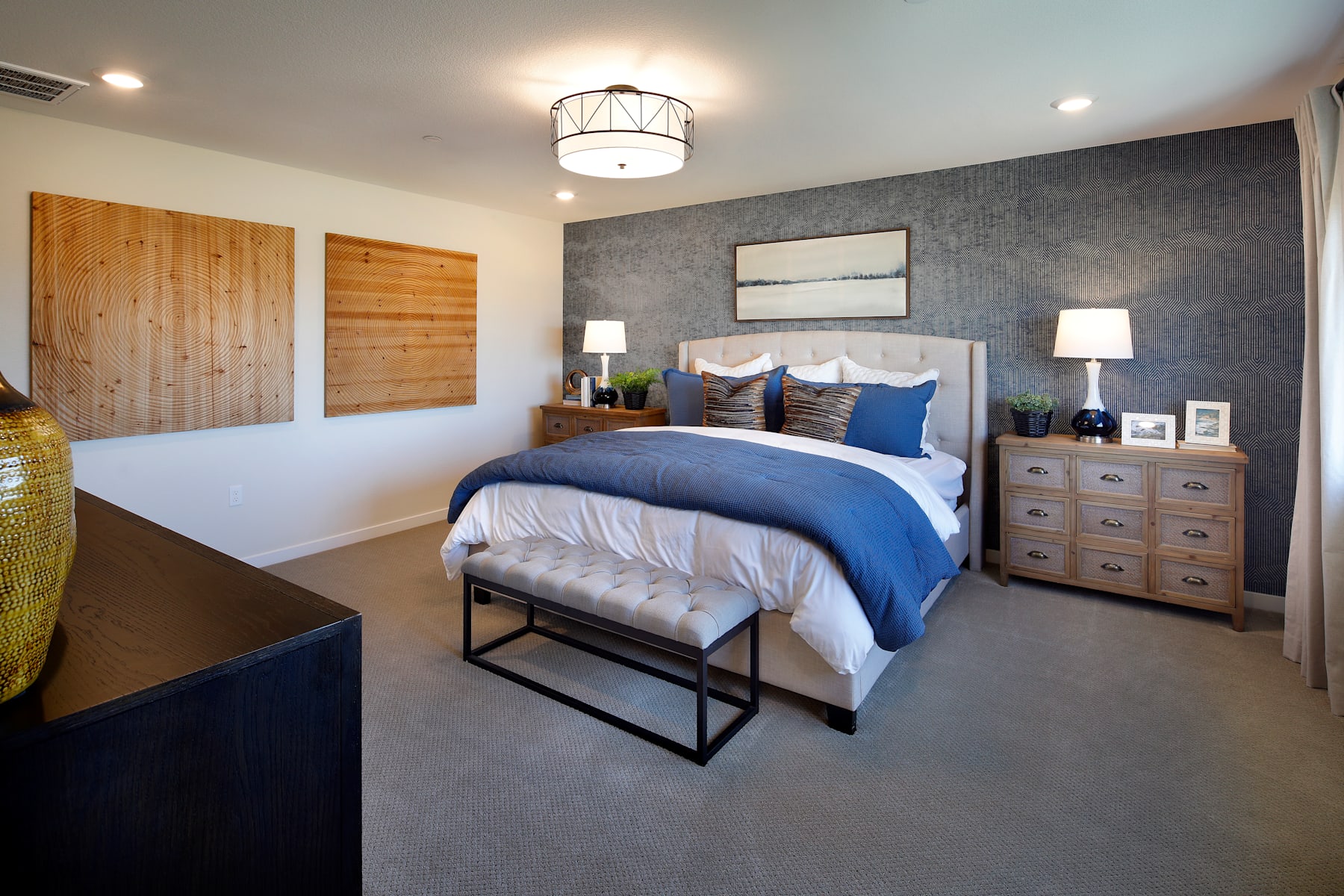 A cozy and modern bedroom with a plush bed, wooden accents, and a stylish chandelier overhead, creating a warm and inviting atmosphere.