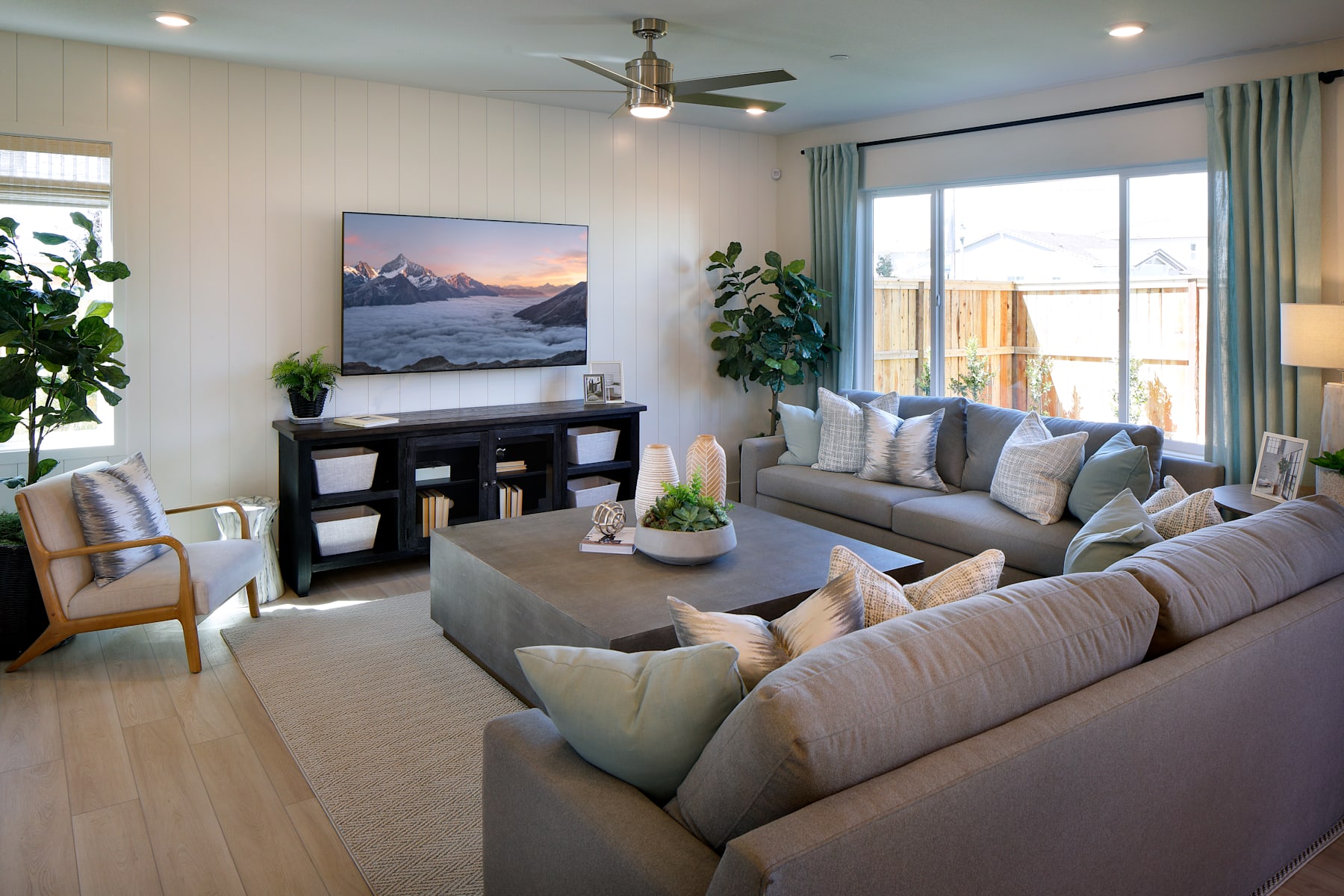 A cozy and inviting living room with a large TV mounted on the wall, plush sofas and armchairs, and a variety of decorative elements such as plants and artwork, creating a warm and comfortable atmosphere.