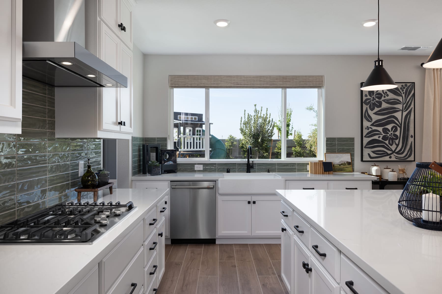A modern, well-equipped kitchen with white cabinets, stainless steel appliances, and a large window overlooking a scenic outdoor view.