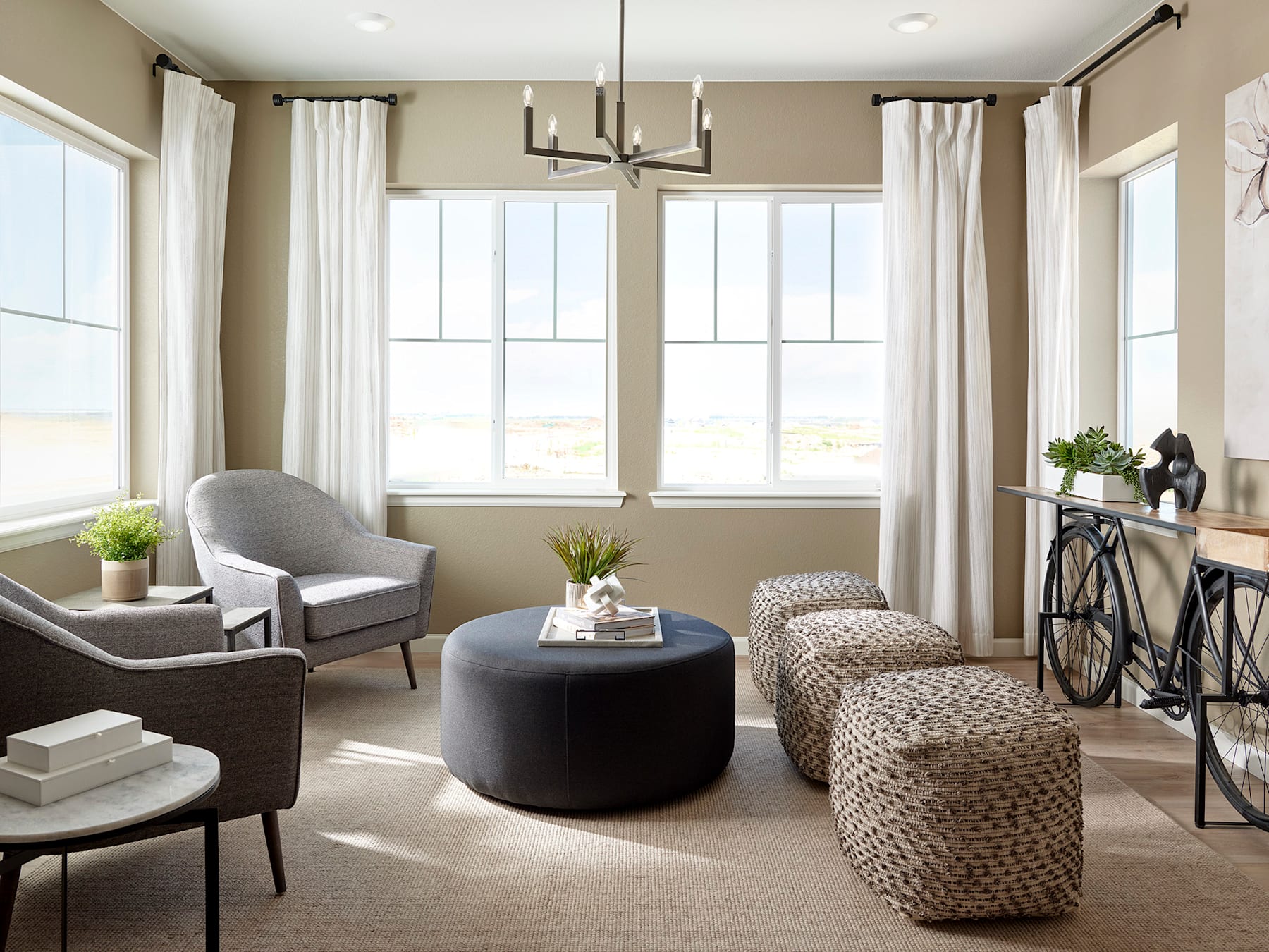 A cozy and inviting living room with large windows, neutral-toned furniture, and decorative accents, creating a warm and welcoming atmosphere.