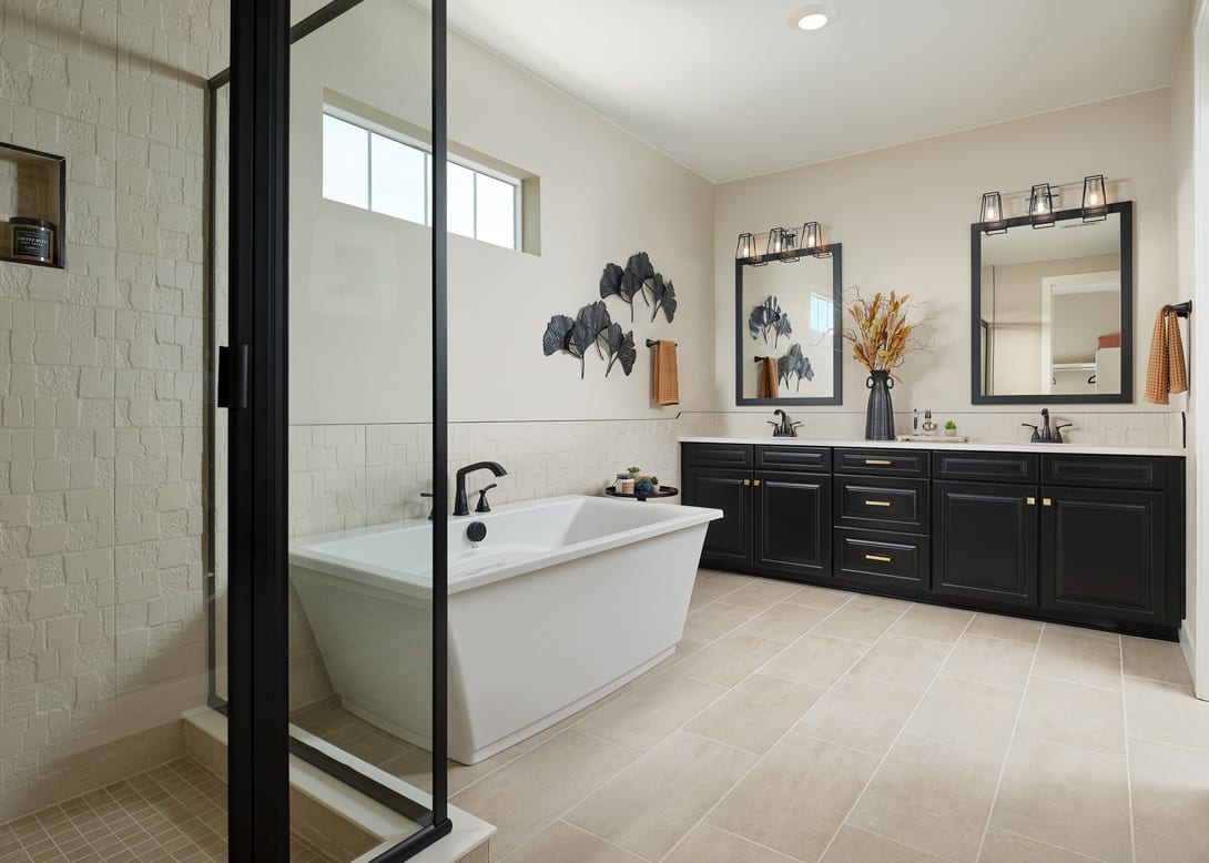 A modern and spacious bathroom with a freestanding bathtub, dark wood vanity cabinets, and decorative wall accents.