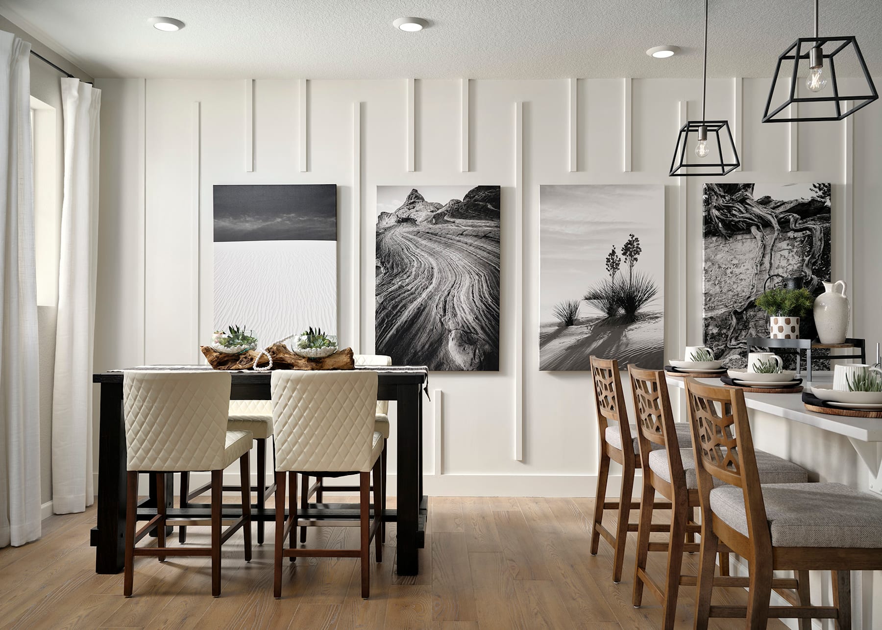 A modern and minimalist dining area with a wooden table and chairs, complemented by large black-and-white landscape photographs on the walls, creating a serene and inviting atmosphere.