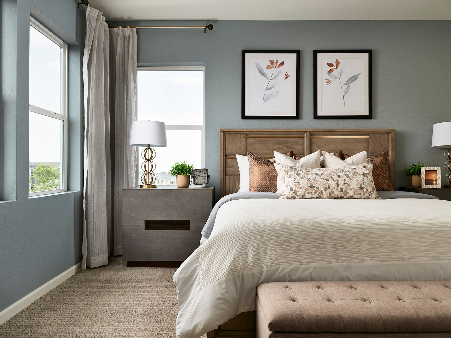 A cozy and inviting bedroom with a wooden headboard, neutral-toned bedding, and framed artwork on the walls, complemented by a window providing natural light.