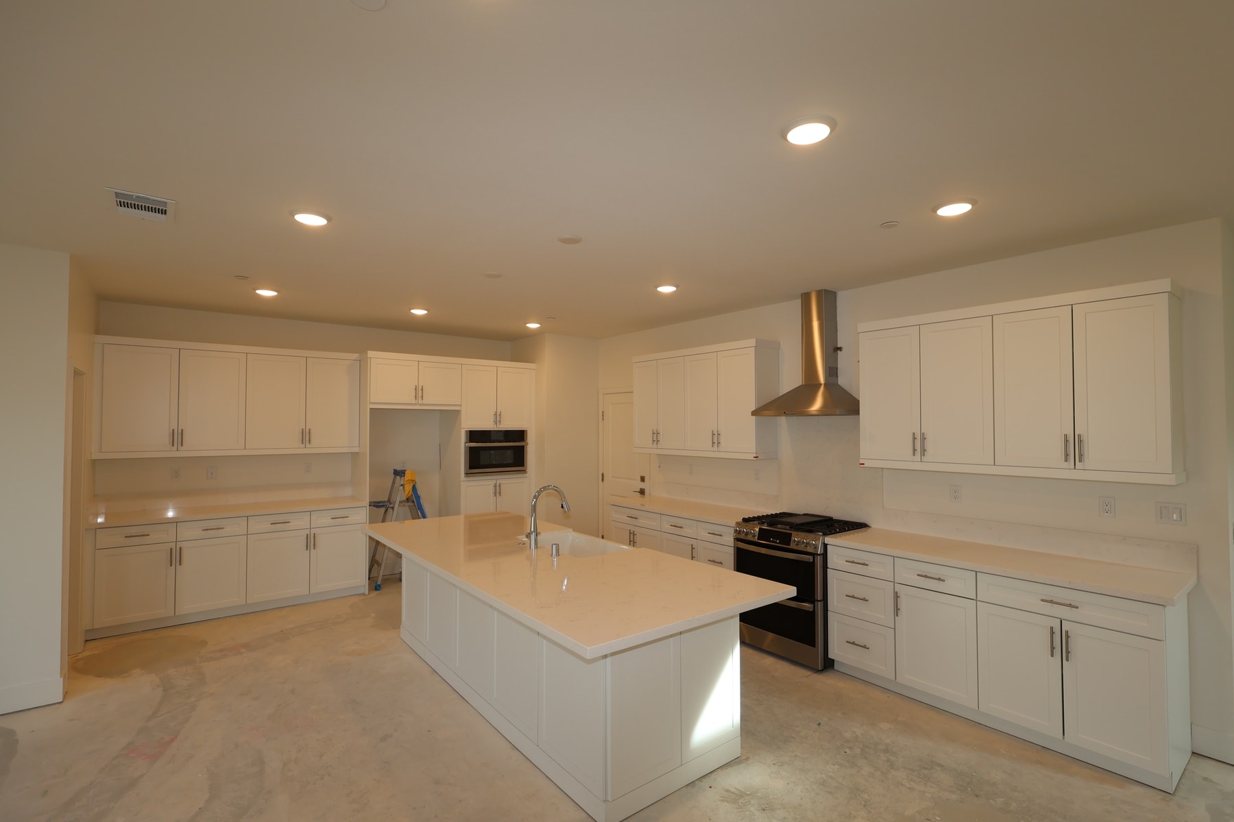 A modern, well-lit kitchen with white cabinets, a central island, and stainless steel appliances.