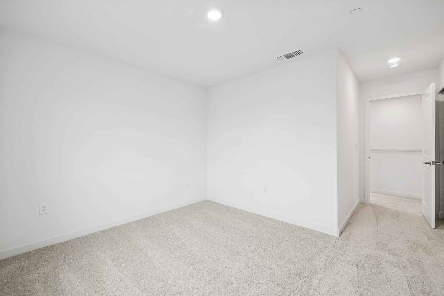 A bright, minimalist room with white walls, a light-colored floor, and a recessed lighting fixture in the ceiling.