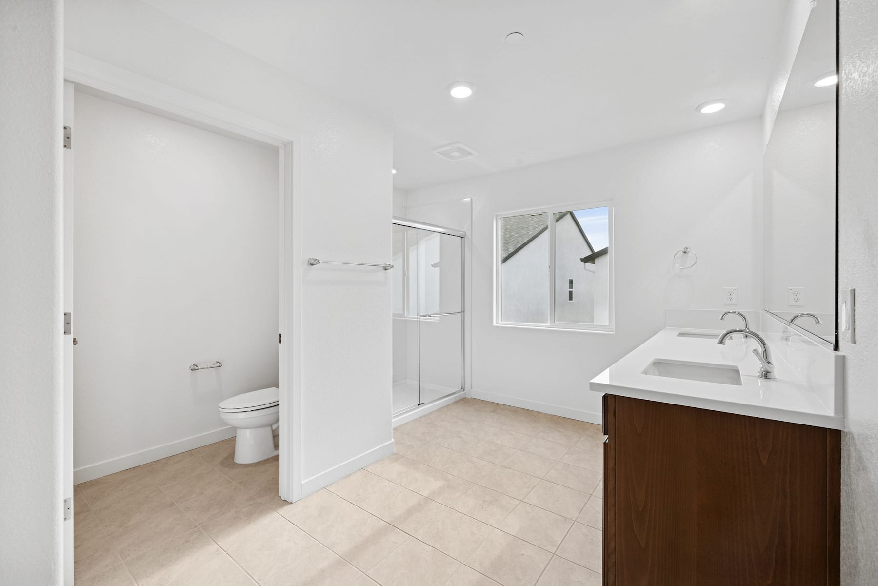 A modern, well-lit bathroom with a vanity, toilet, and shower visible, set against a neutral color palette.