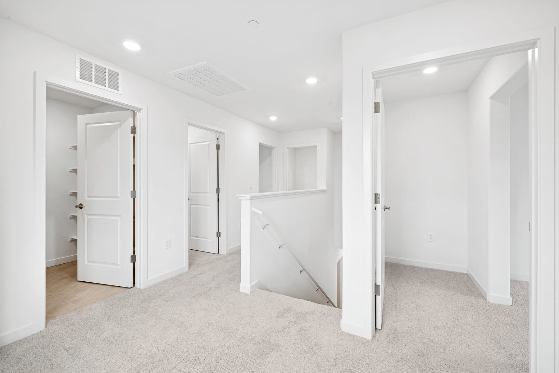 A bright, spacious hallway with white walls, doors, and light-colored flooring, creating a clean and minimalist atmosphere.