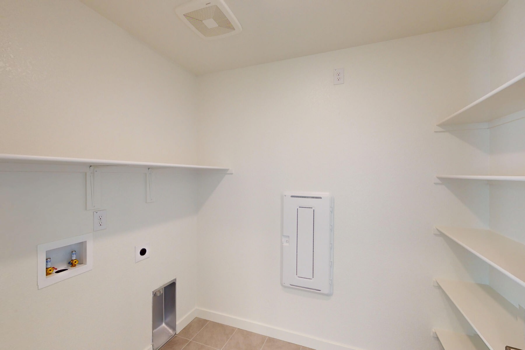 A small, minimalist room with white walls, shelves, and a light switch on the wall.