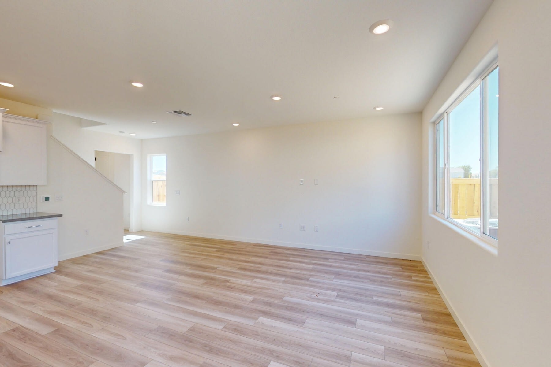 A spacious, well-lit room with a hardwood floor and a large window, providing a bright and airy atmosphere.