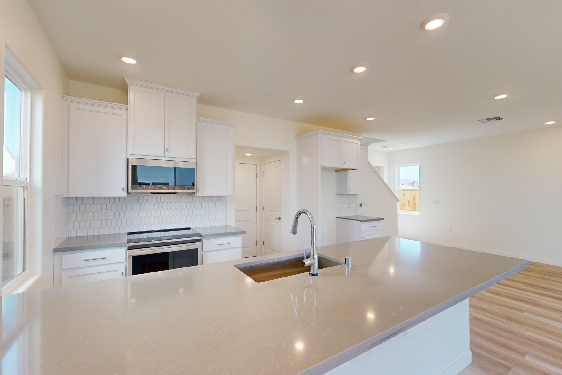 A modern, bright, and spacious kitchen with white cabinets, stainless steel appliances, and a large countertop island.