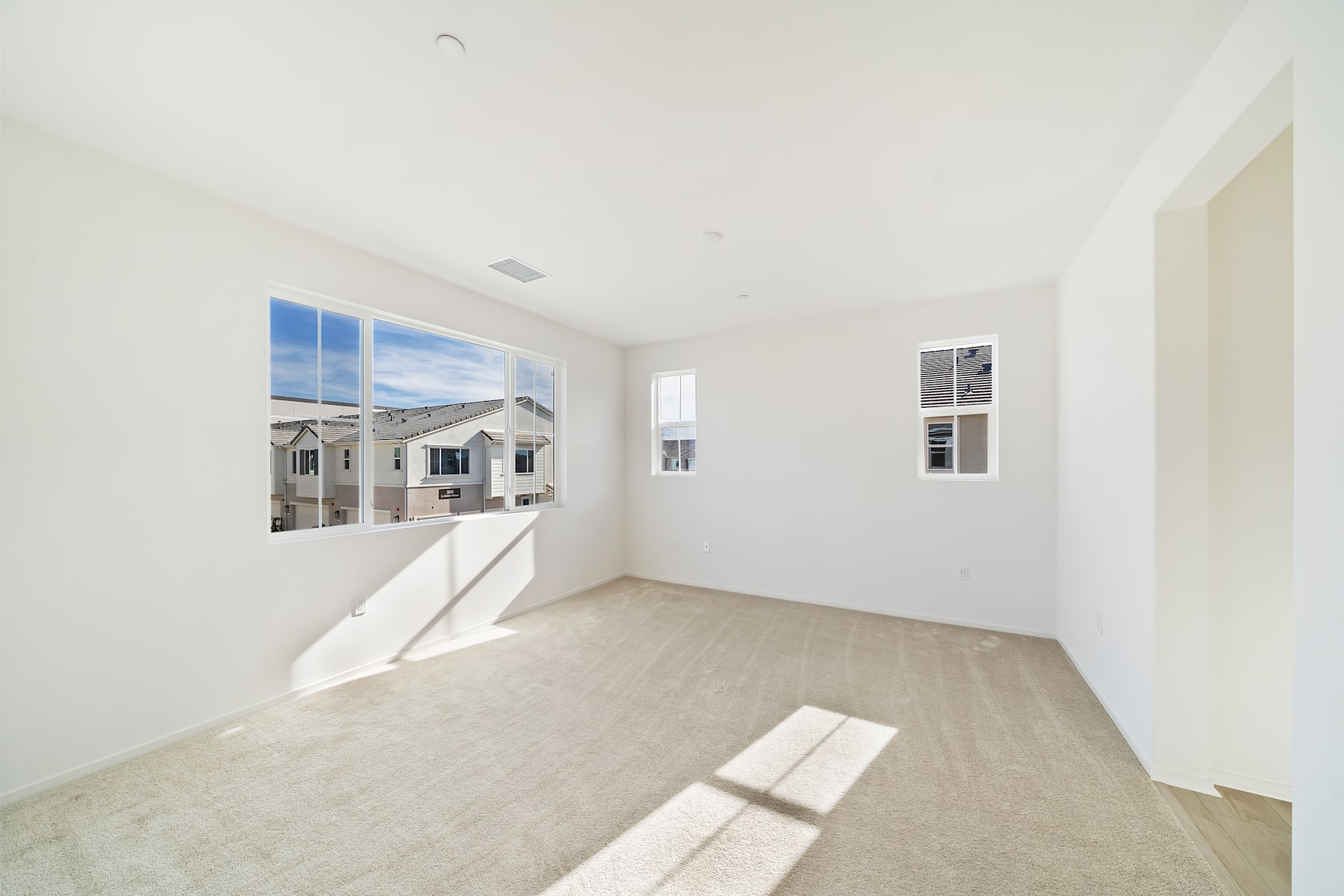 A bright, spacious room with large windows overlooking a residential neighborhood in the background.