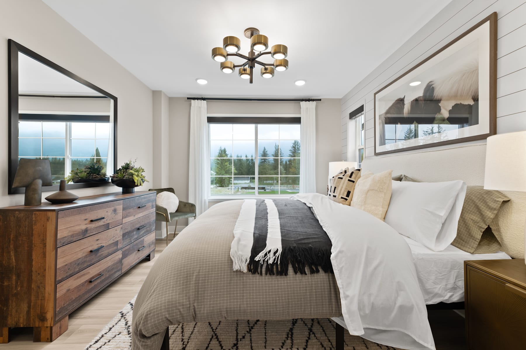 A spacious and well-designed bedroom with a large window, a wooden dresser, and a chandelier hanging from the ceiling, creating a cozy and inviting atmosphere.