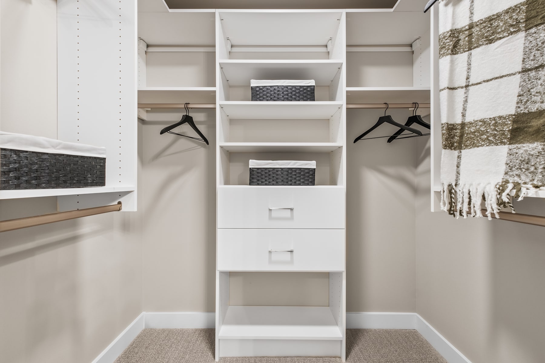 A well-organized and spacious walk-in closet with white shelves, drawers, and hanging rods, providing ample storage and organization for clothing and accessories.