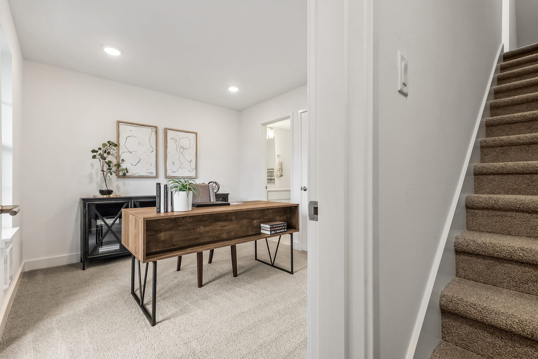 A modern and minimalist entryway with a wooden console table, decorative items, and a staircase leading to the upper level.
