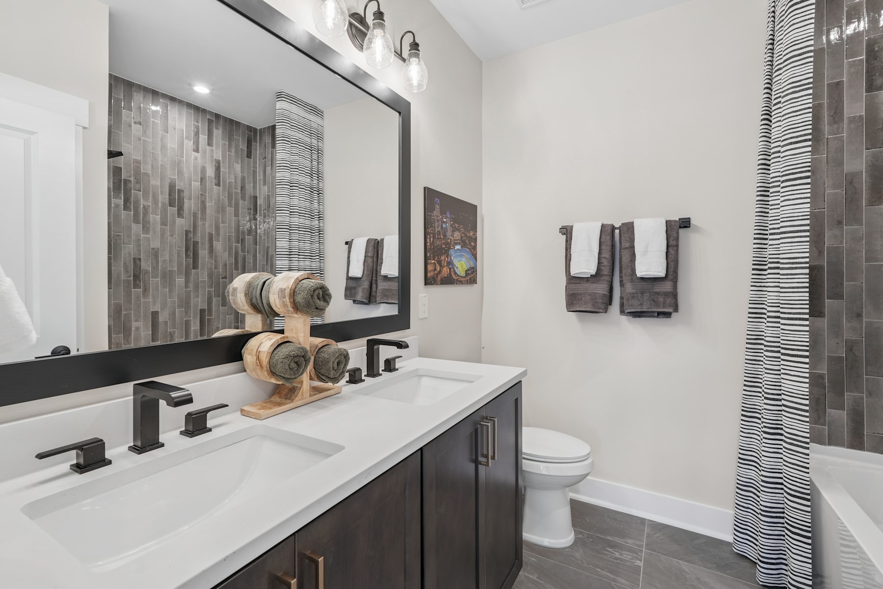 A modern and stylish bathroom with a double vanity, a patterned tile backsplash, and decorative towel racks on the wall.