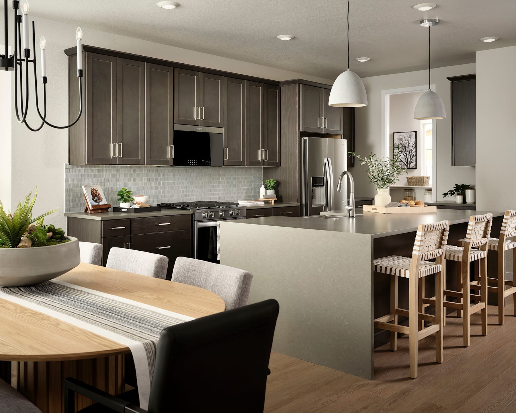 A modern and spacious kitchen with dark wood cabinets, a large island with bar stools, and a dining table in the foreground.