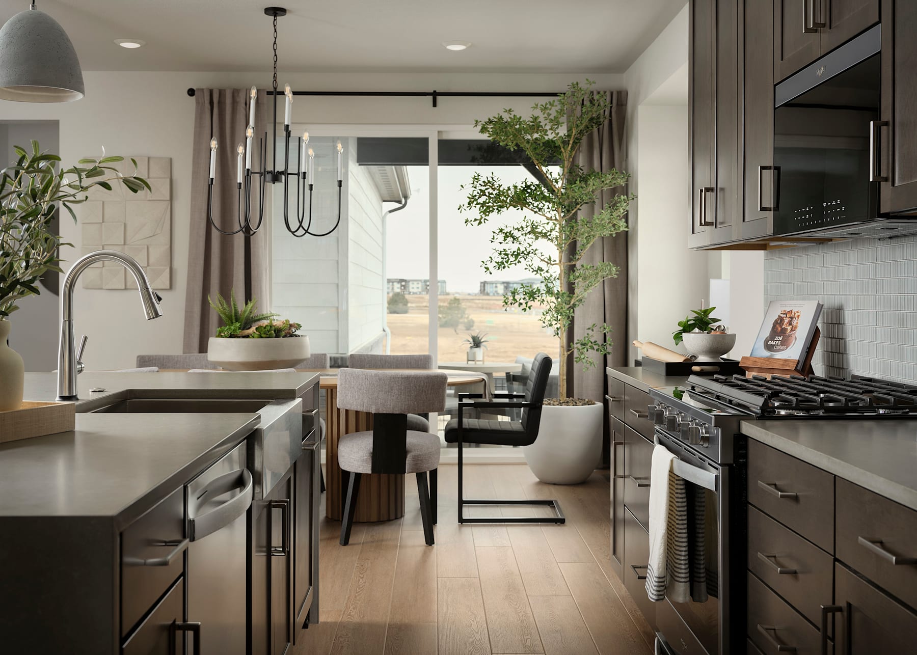 A modern and cozy kitchen with a sleek design, featuring dark cabinets, stainless steel appliances, and a large window overlooking a lush outdoor area.