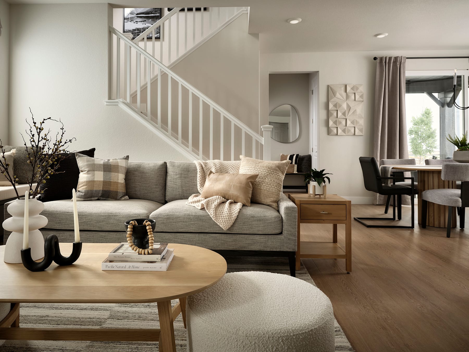 A cozy and inviting living room with a plush gray sofa, wooden coffee table, and decorative accents, complemented by a staircase and open-concept layout in the background.