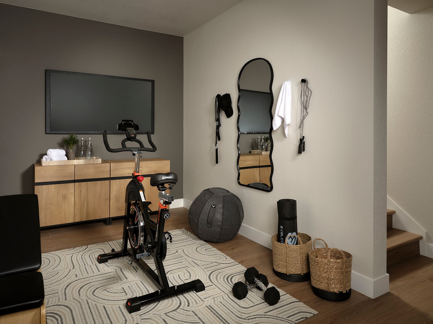 A modern and minimalist home gym setup with a stationary bike, mirrors, and various fitness equipment and accessories arranged in a well-organized manner.