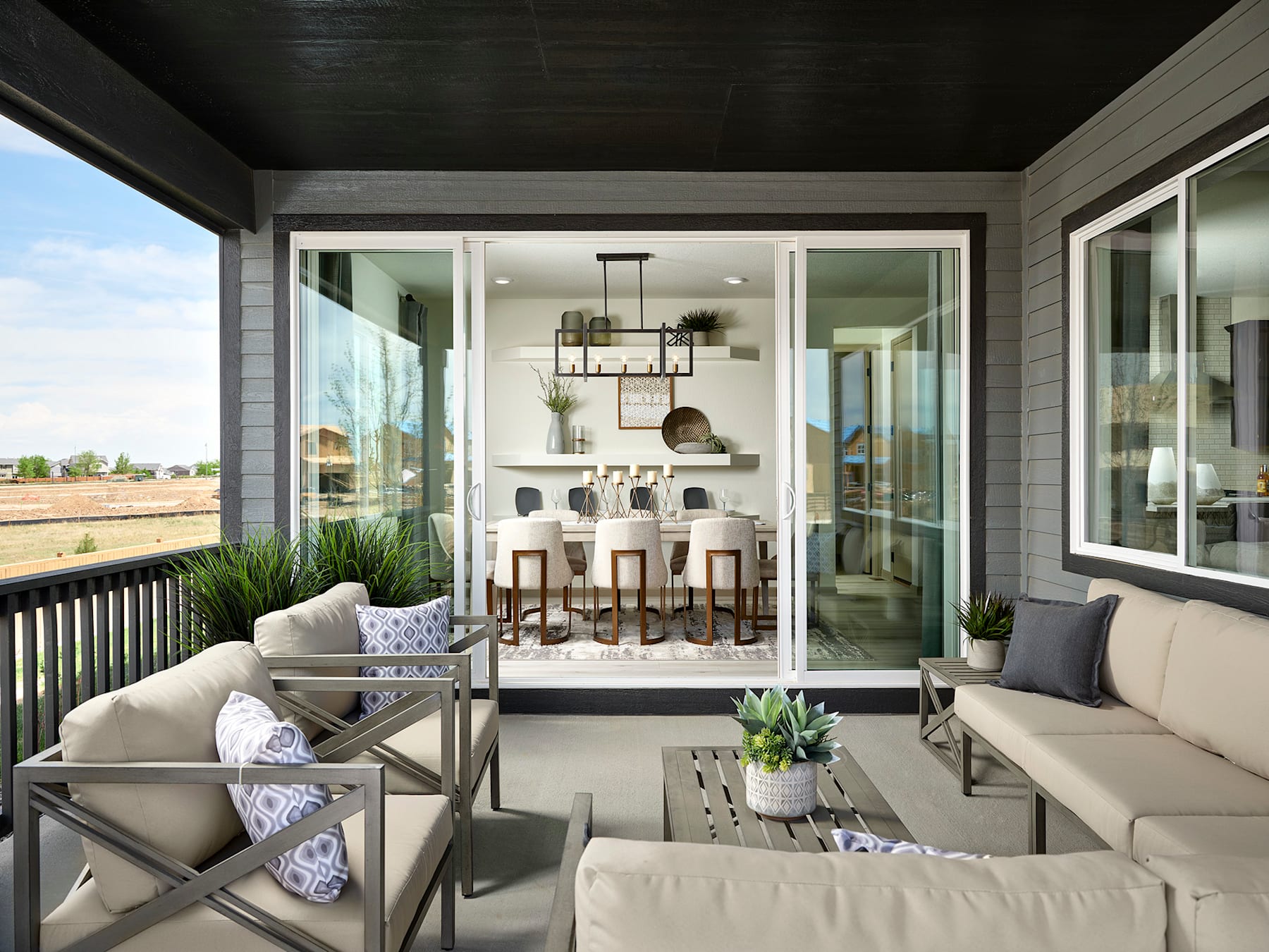 A cozy and inviting outdoor living space with comfortable seating, a glass-enclosed interior, and a view of the surrounding landscape.