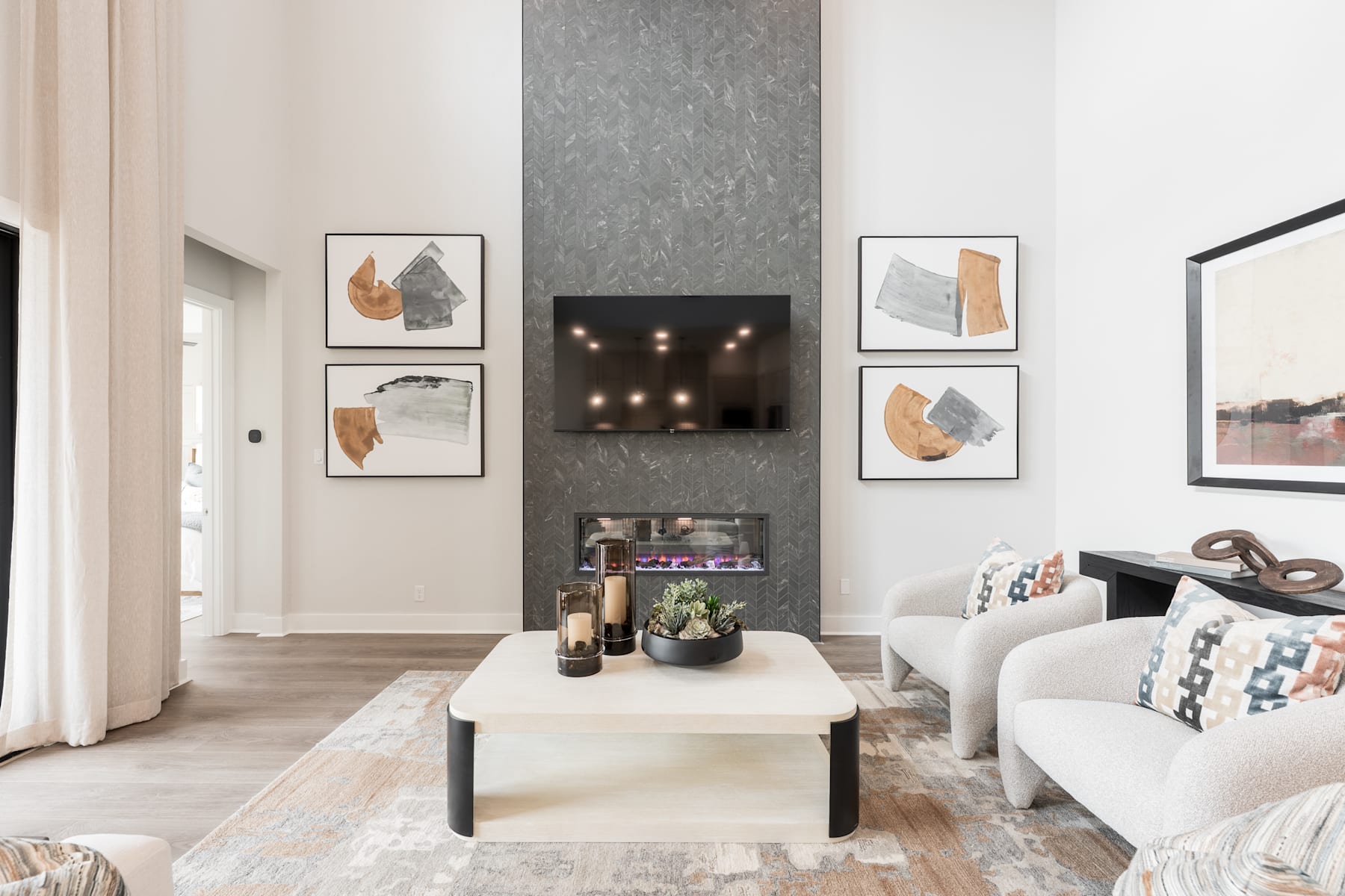 A modern and minimalist living room with a white sofa, a low wooden coffee table, and abstract artwork adorning the walls.