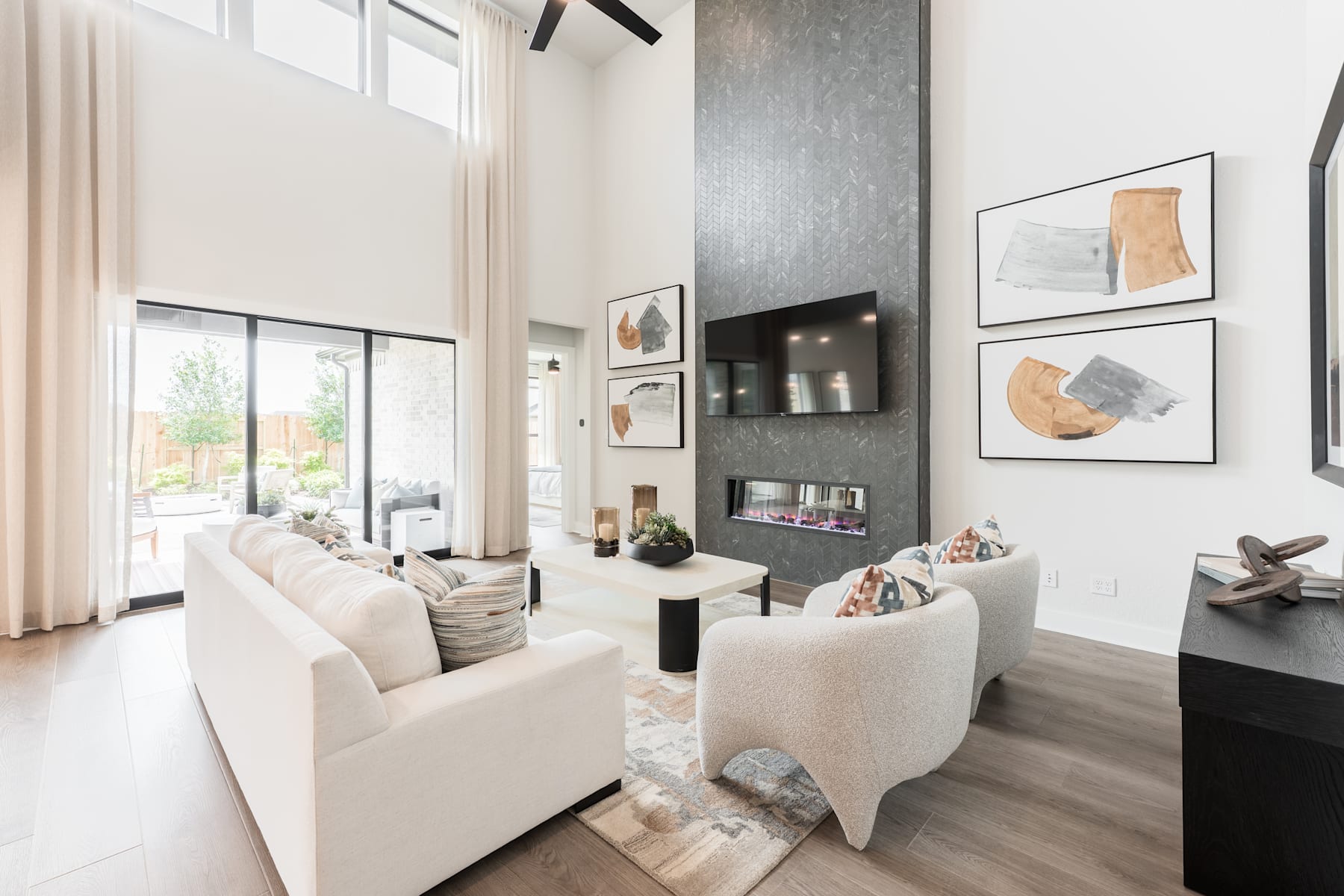 A modern and minimalist living room with large windows, neutral-toned furniture, and abstract artwork adorning the walls.