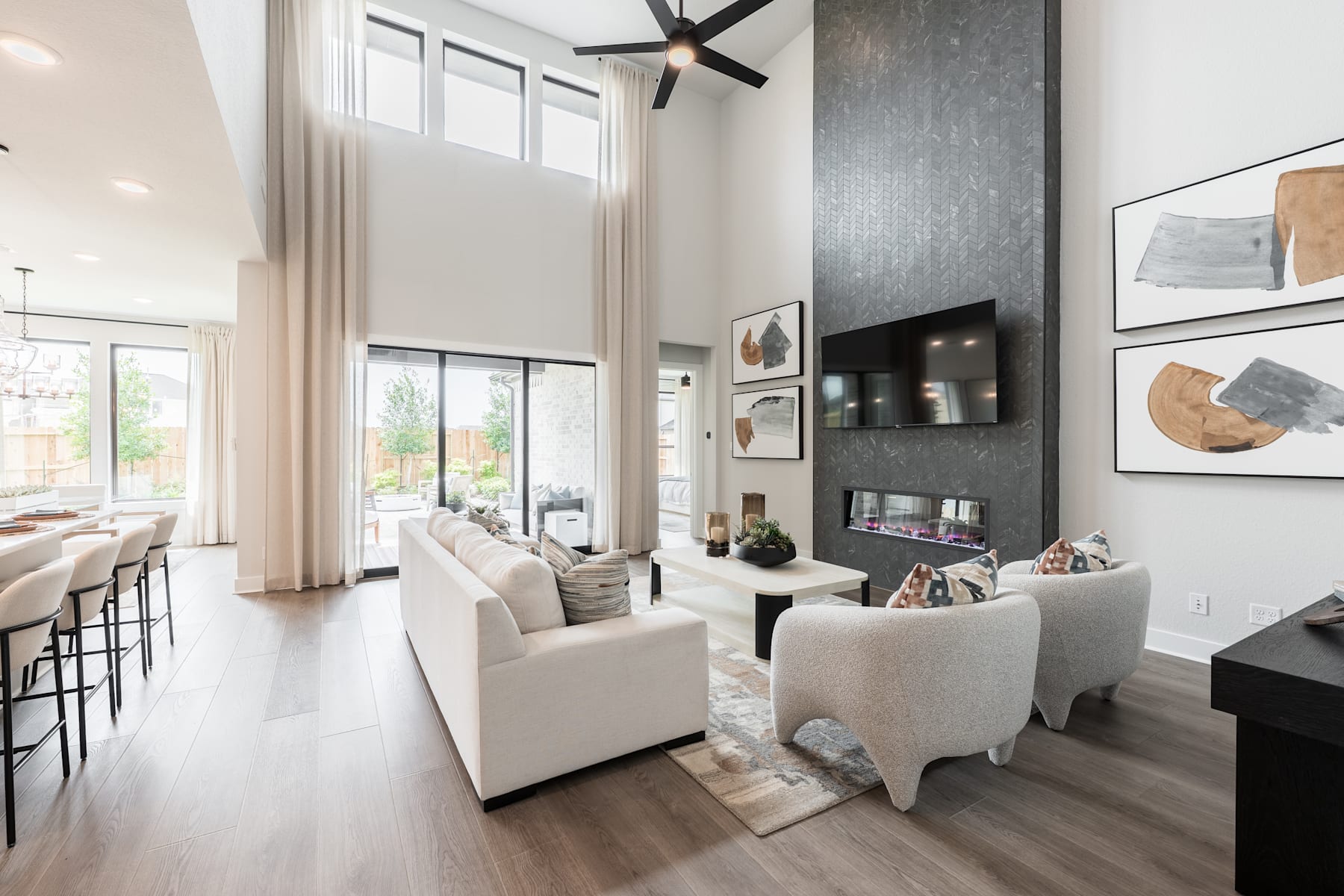 A spacious and modern living room with white furniture, high ceilings, and large windows overlooking a scenic outdoor view.