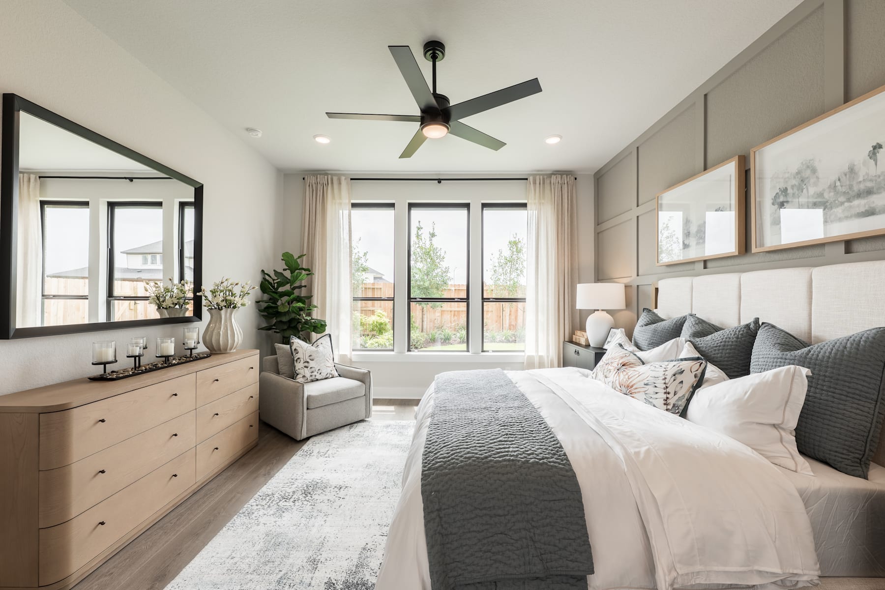 A cozy and modern bedroom with a large bed, neutral-toned decor, and a ceiling fan providing a comfortable atmosphere.