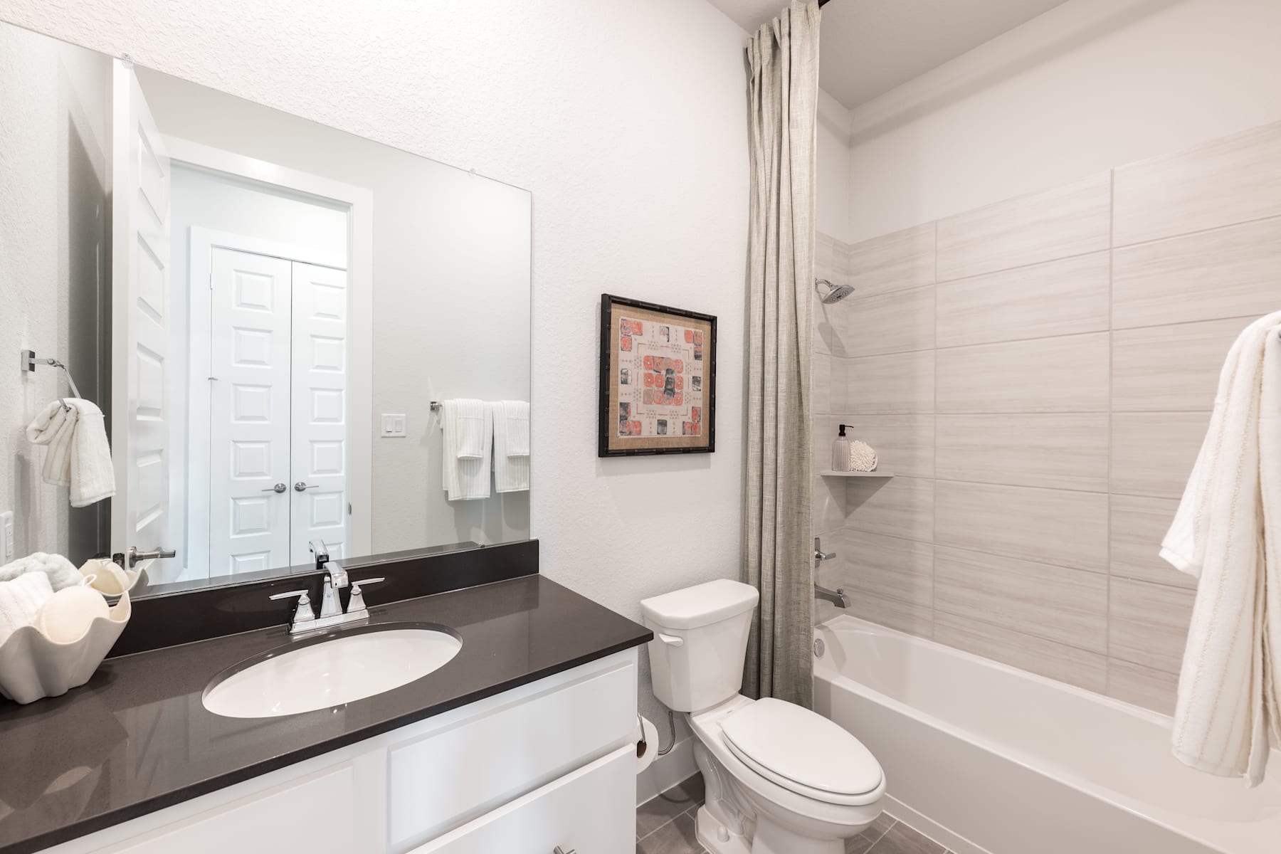 A modern and well-designed bathroom with a vanity, toilet, and bathtub, featuring a neutral color scheme and clean, minimalist aesthetic.