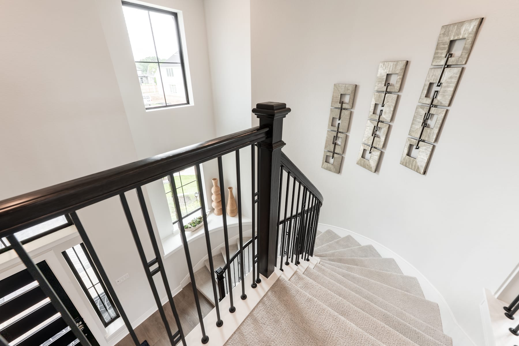 A staircase with a dark wooden railing leads up to a landing, where decorative wall art is displayed against a white wall.