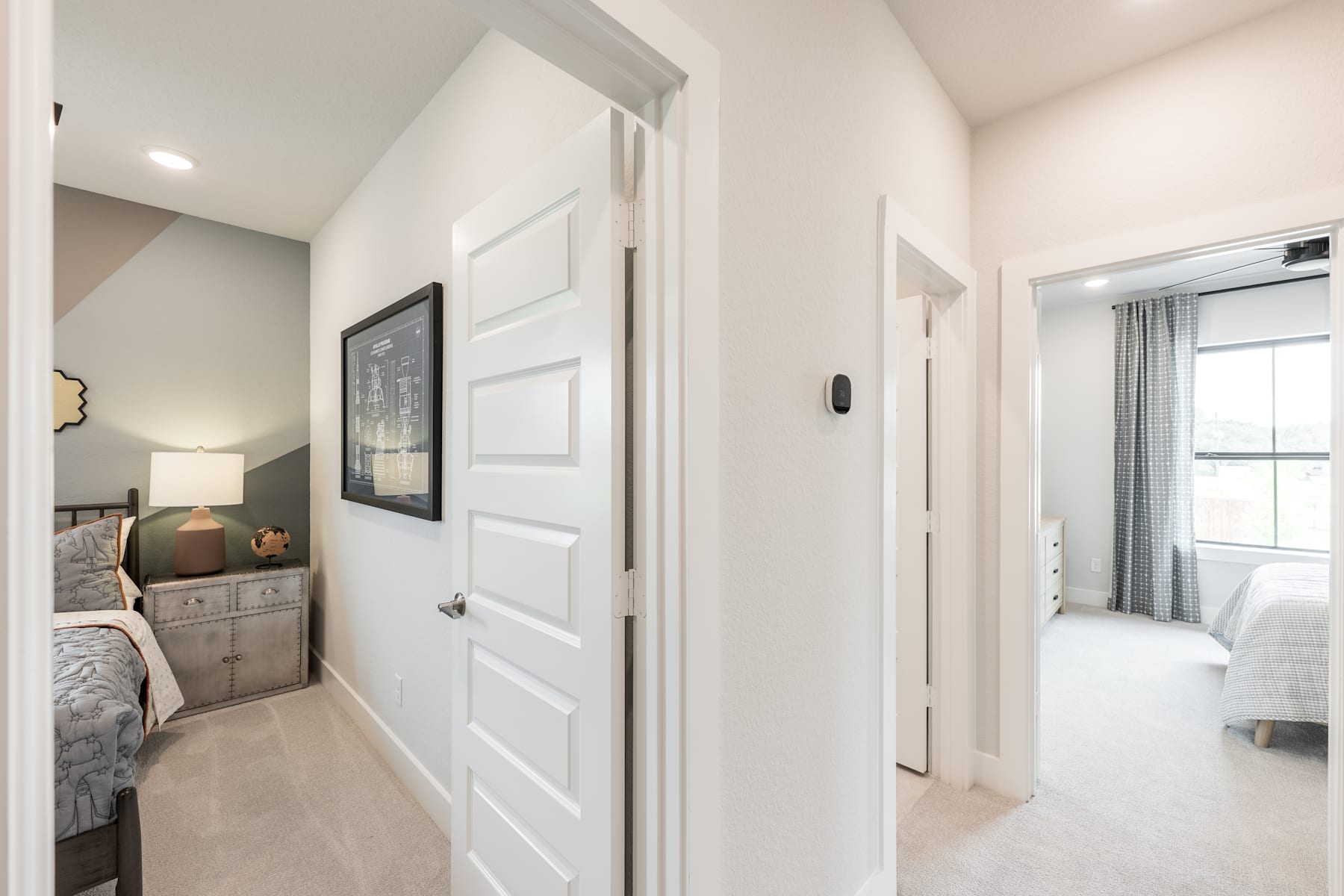 A bright and airy bedroom with a white door leading to an adjacent room, featuring a neutral color scheme and minimalist decor.