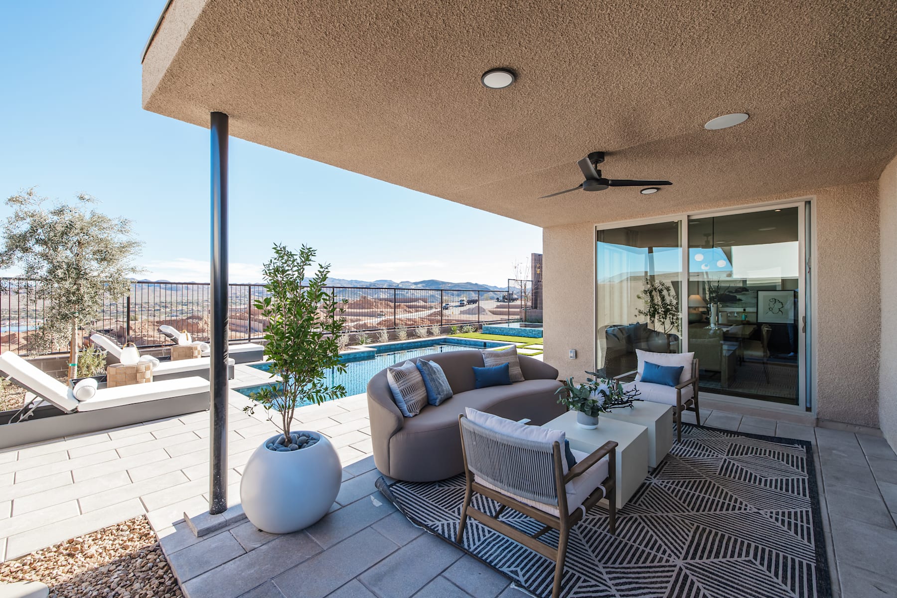 A cozy outdoor patio with comfortable seating, potted plants, and a view of the surrounding landscape, including mountains in the distance.