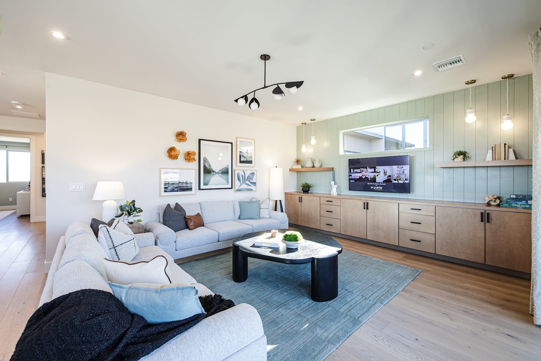 A modern and cozy living room with a comfortable sofa, a wooden cabinet, and various decorative elements, set against a light-colored wall and floor.