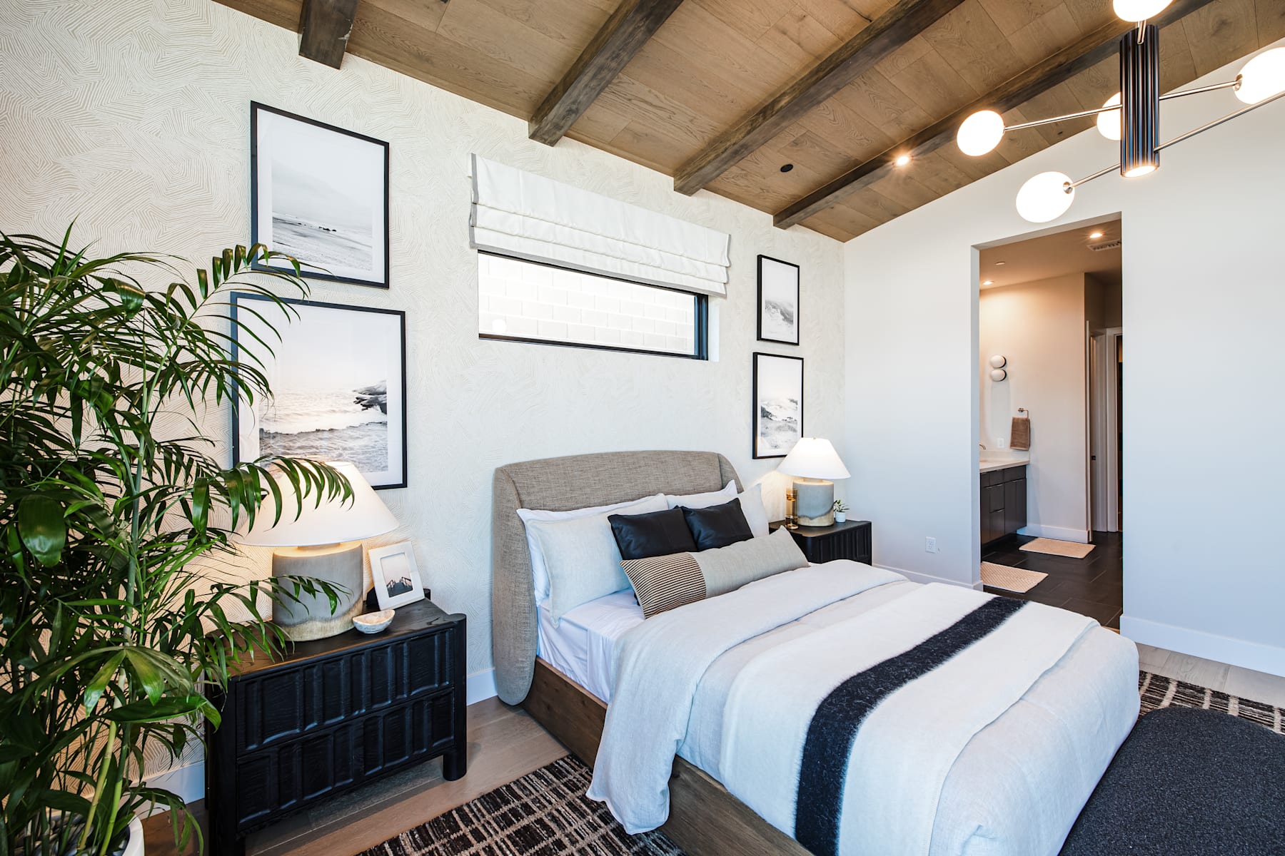 A cozy and well-designed bedroom with a comfortable bed, wooden ceiling beams, and decorative plants adding a touch of nature to the space.