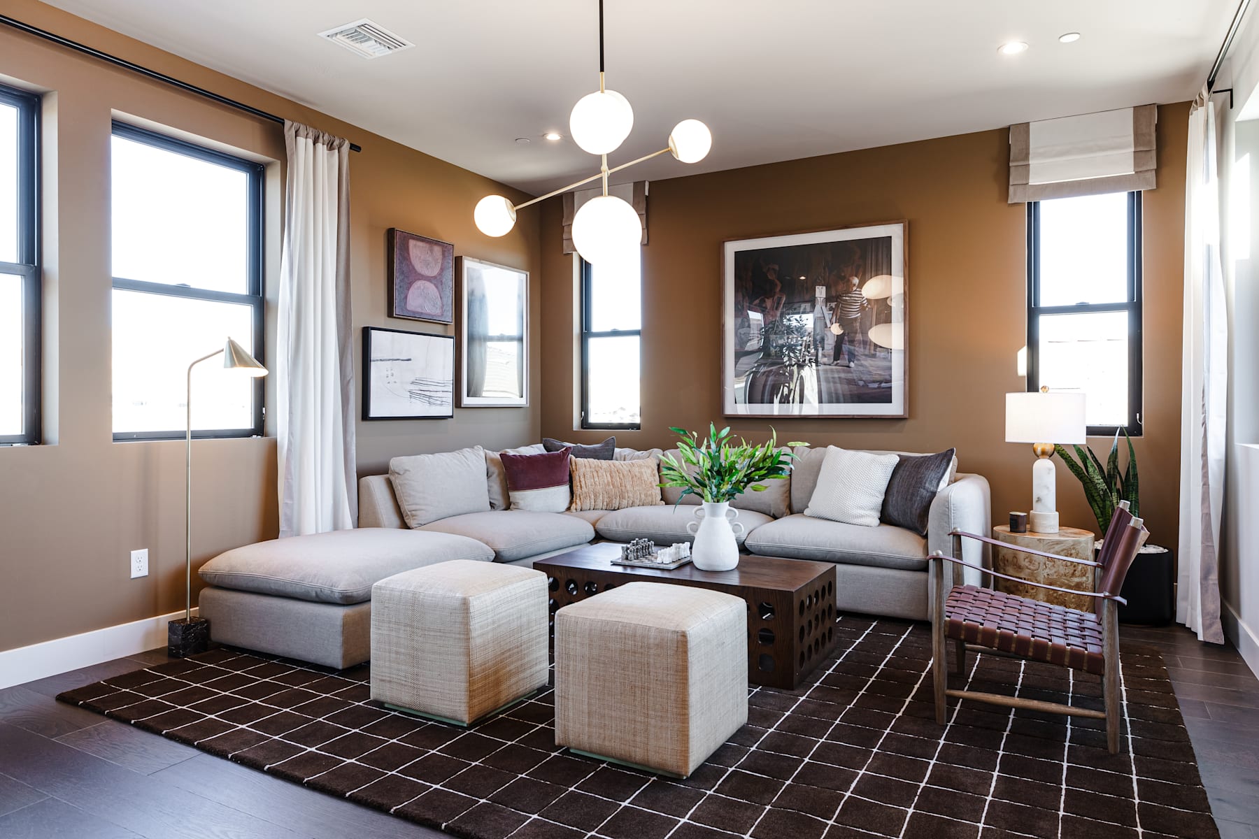 A cozy and inviting living room with a plush gray sectional sofa, decorative pillows, and a wooden coffee table surrounded by large windows that let in natural light.