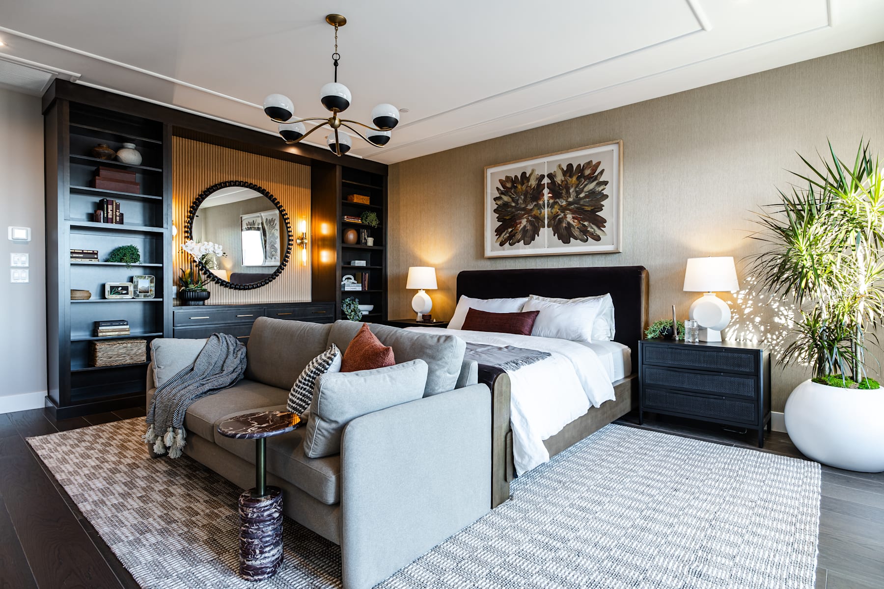 A cozy and well-decorated bedroom with a large bed, plush seating, and a variety of decorative elements, including a chandelier, shelving, and artwork on the walls.