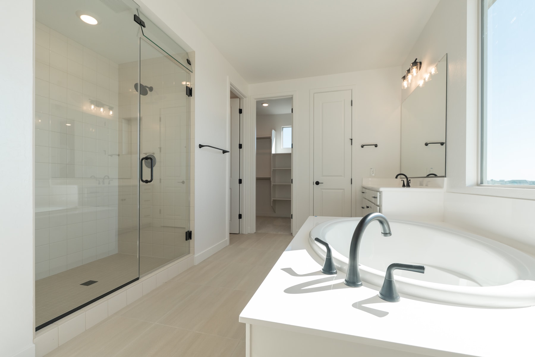A modern, well-lit bathroom with a large vanity, a freestanding bathtub, and a glass-enclosed shower area.