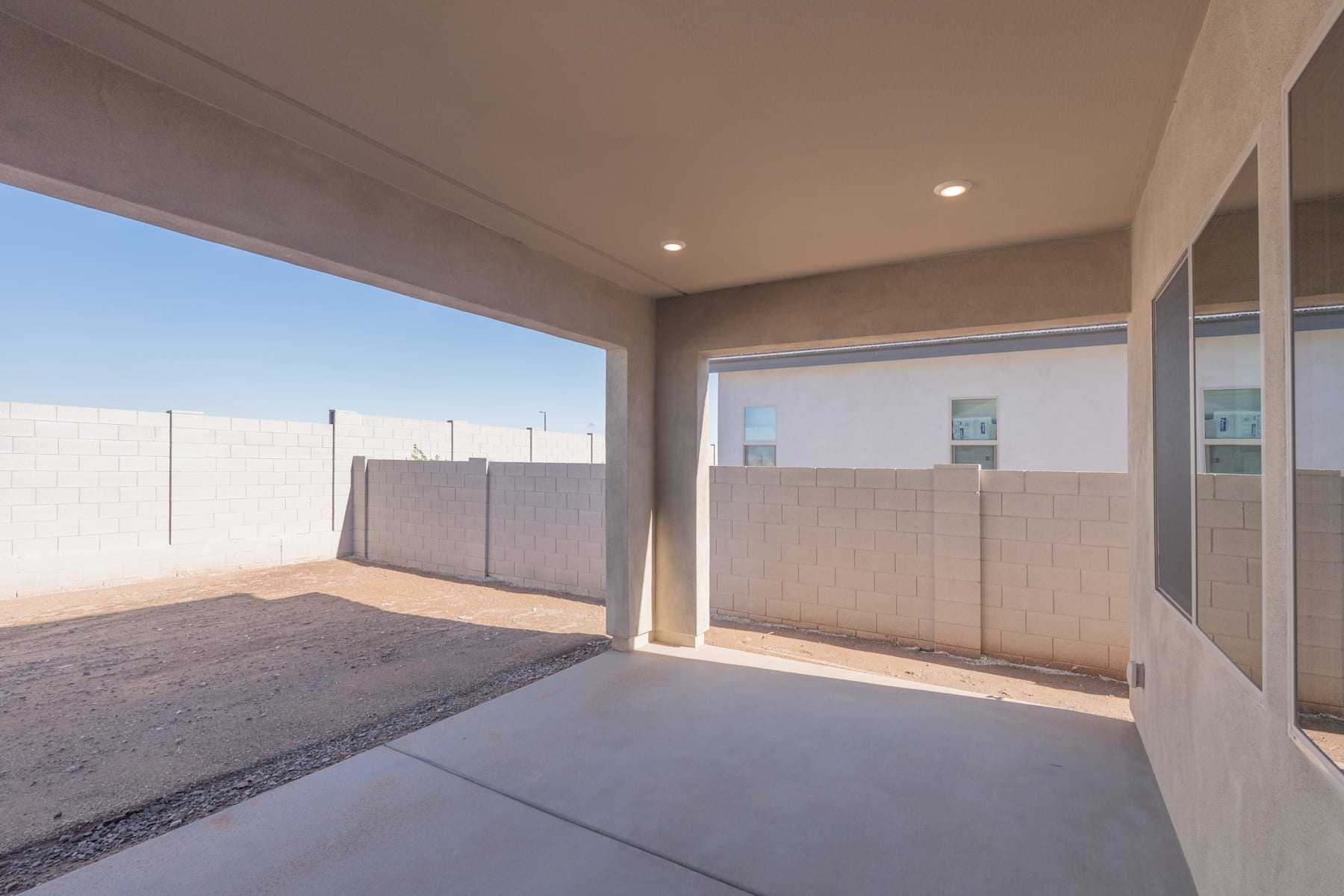 A spacious, well-lit patio with a concrete floor and a white wall in the background, providing a clean and modern aesthetic.