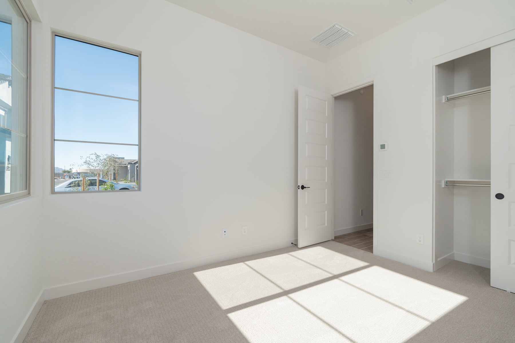 A bright and spacious room with a large window, a white door, and built-in shelving, creating a clean and minimalist atmosphere.