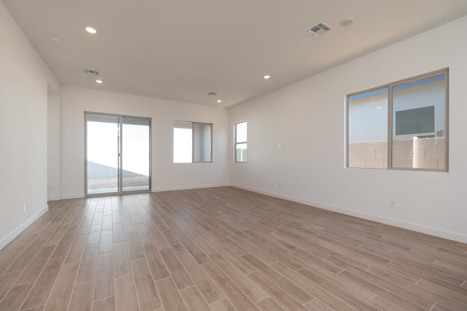 A spacious, well-lit room with a hardwood floor and large windows providing a scenic view in the background.