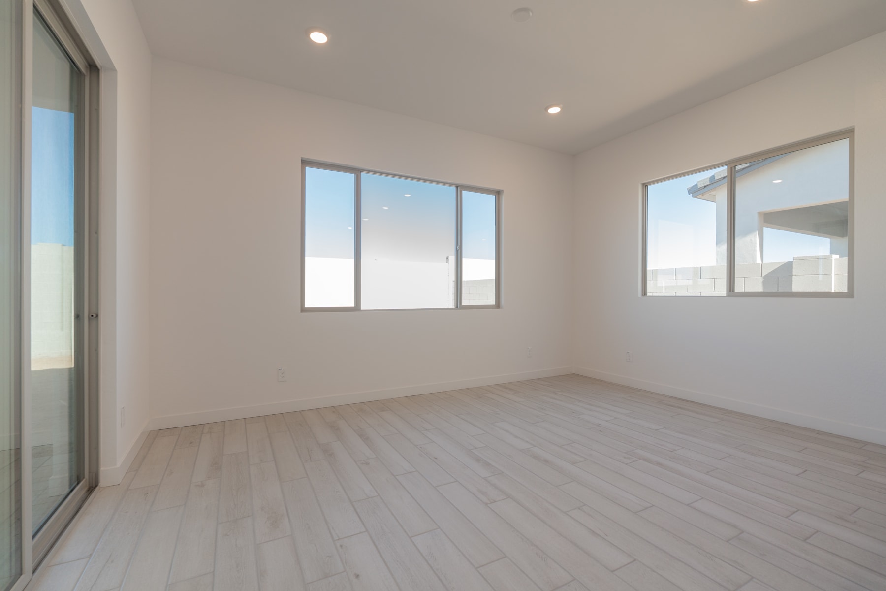 A bright, spacious room with large windows, a hardwood floor, and a minimalist, clean design.