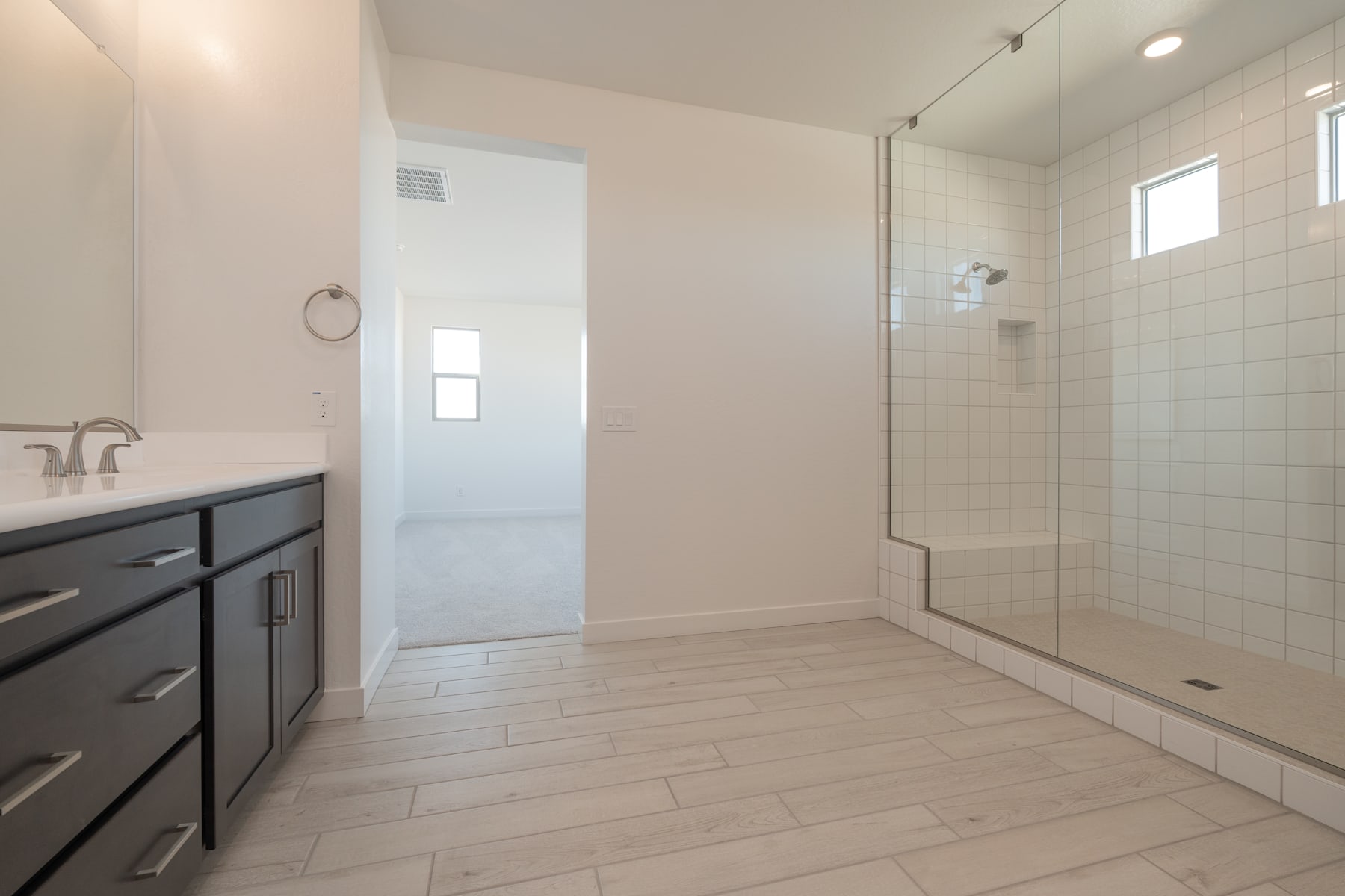 A modern, well-lit bathroom with a vanity, tiled floor, and a glass-enclosed shower area.