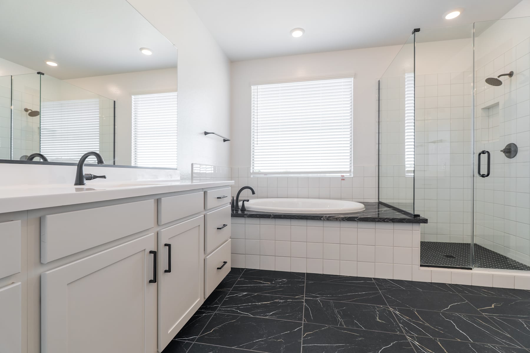 A modern and spacious bathroom with a vanity, a bathtub, and a shower enclosure, featuring a neutral color scheme and sleek design elements.