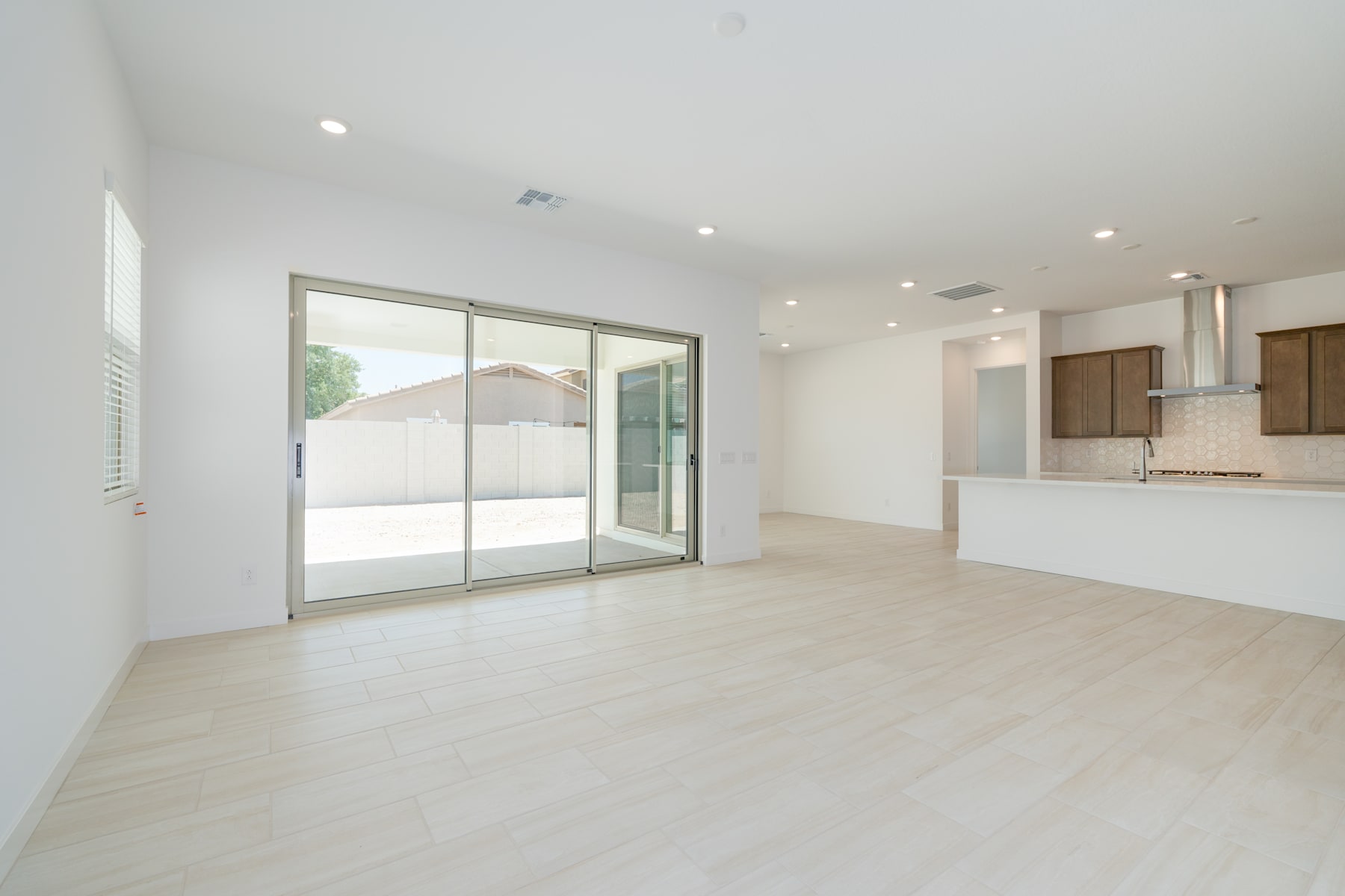 A spacious, open-concept living area with large sliding glass doors leading to an outdoor space, featuring a minimalist and modern design aesthetic.