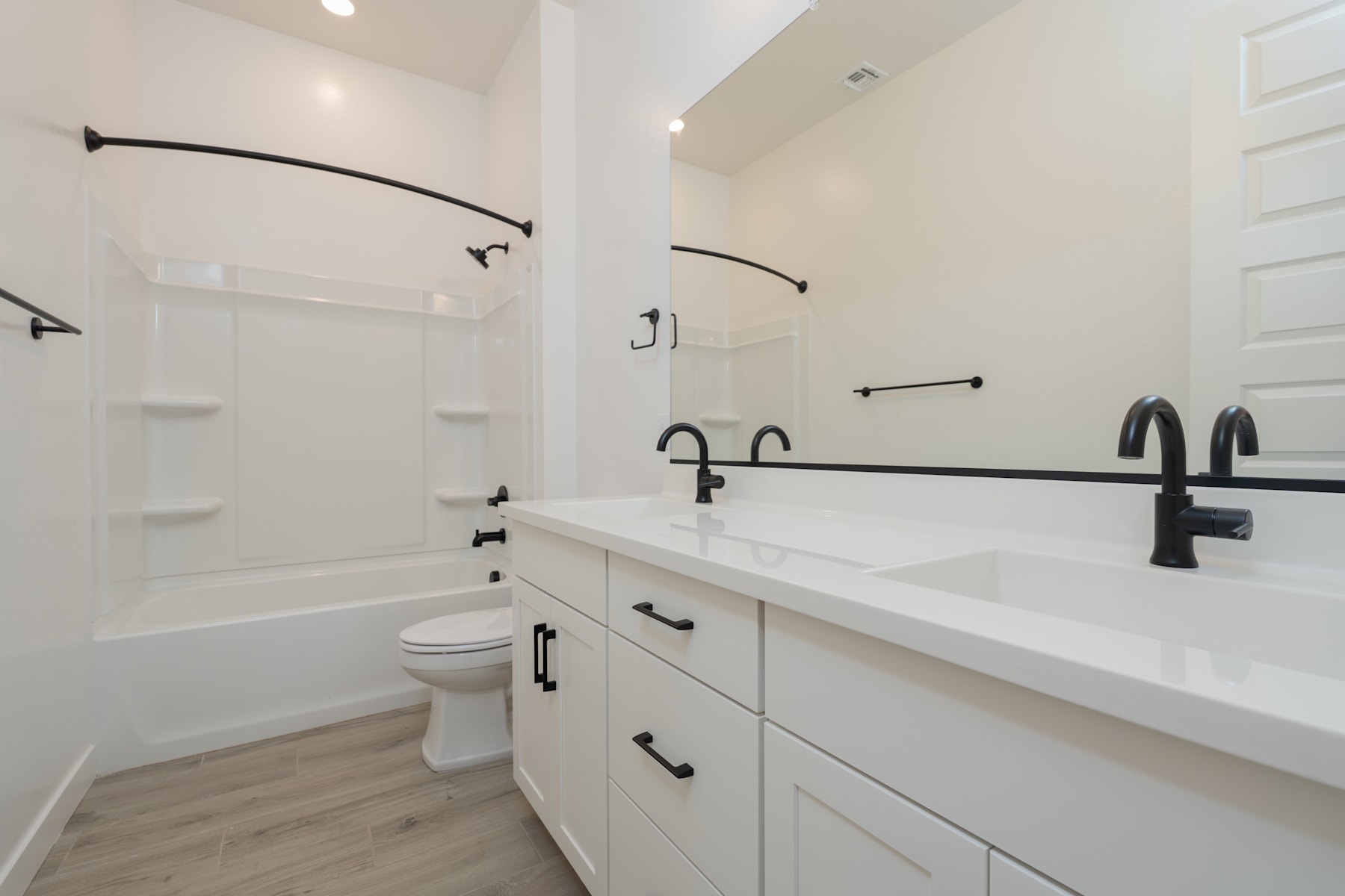 A modern, minimalist bathroom with white cabinets, black fixtures, and a sleek, clean design.