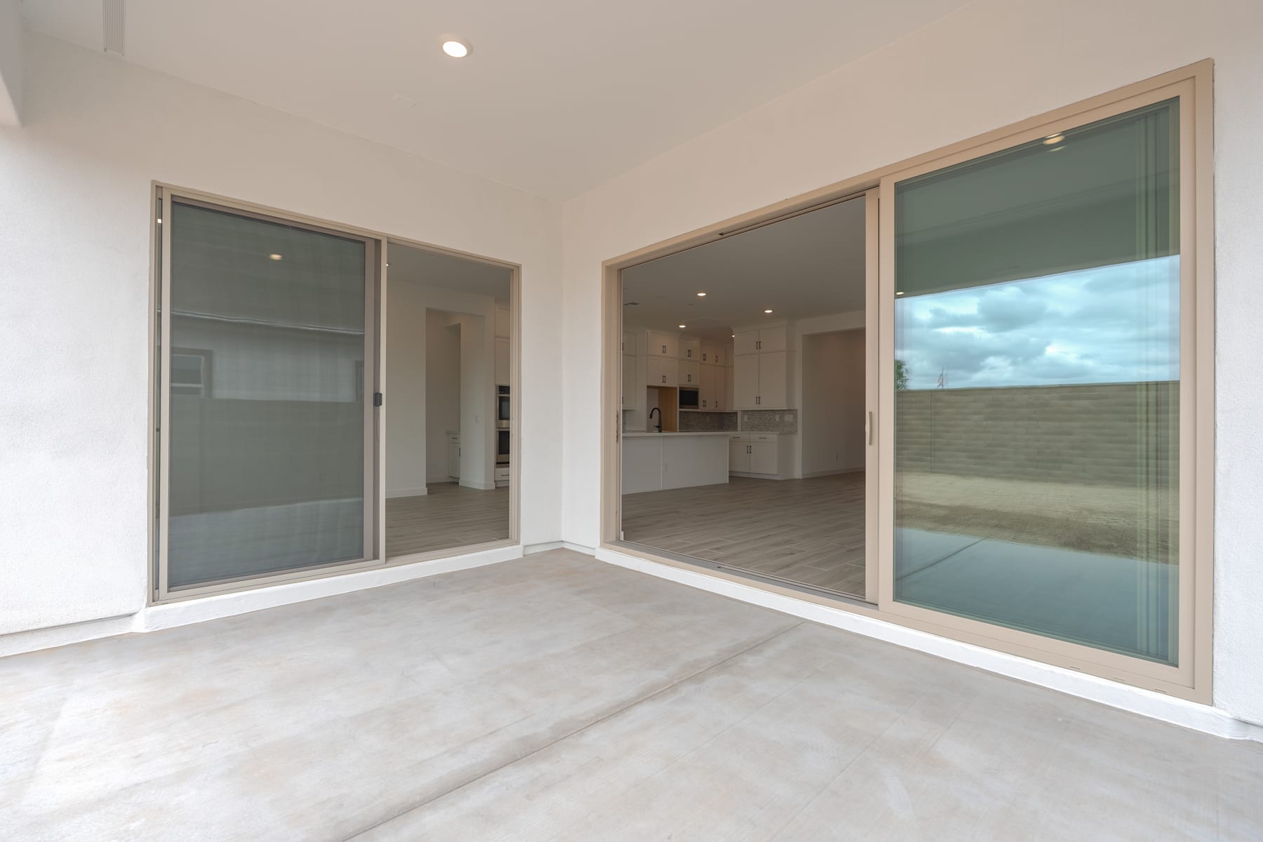 A spacious, modern room with large glass sliding doors leading to an outdoor area, showcasing a minimalist and clean interior design.
